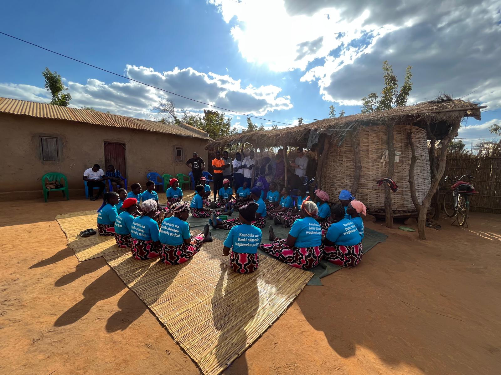 A women's savings and loan group meeting under the open sky in rural Malawi